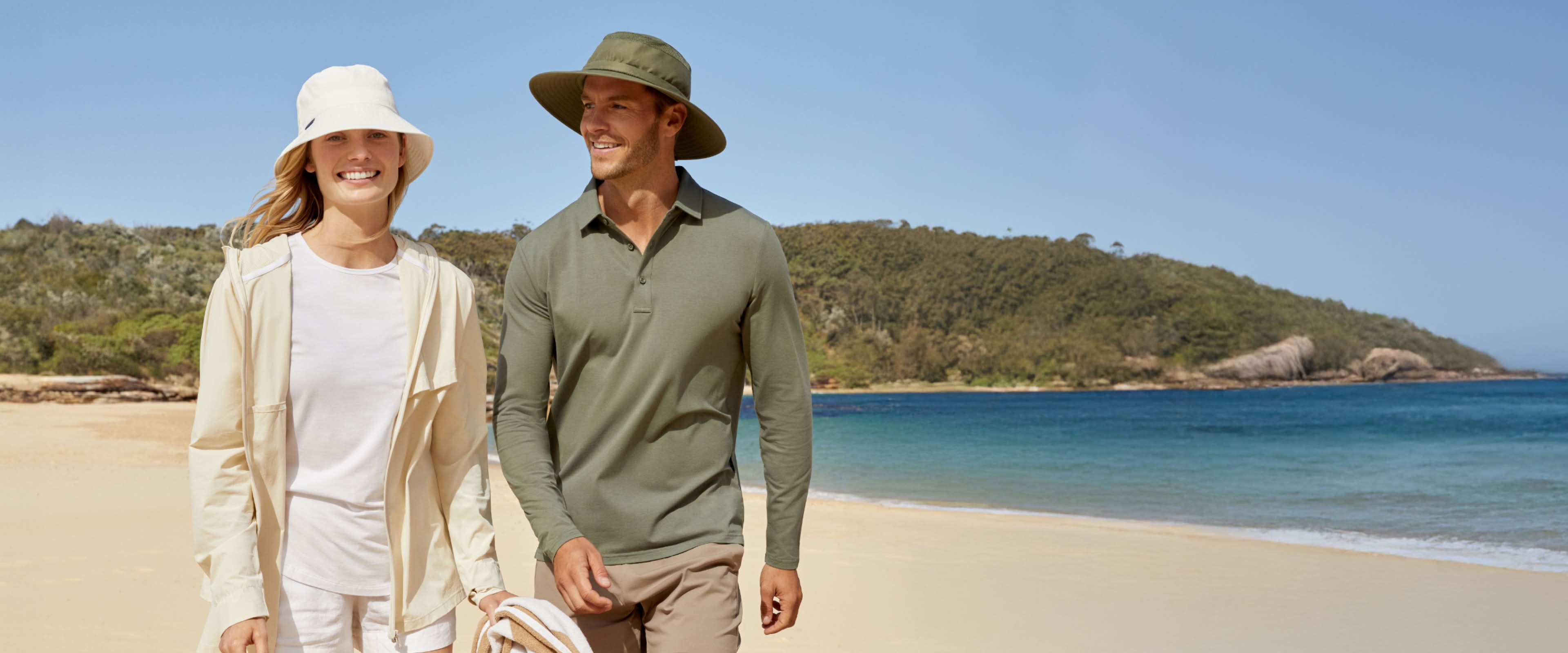 Man and woman walking on a beach with a scenic background