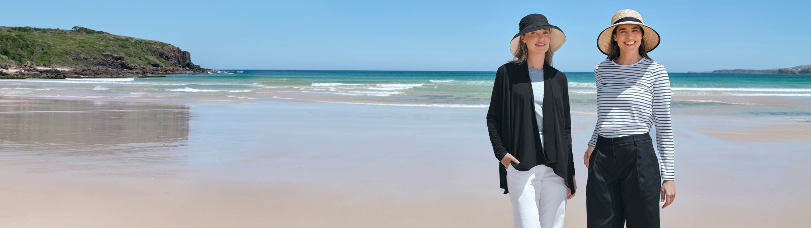 Two people standing on a beach with ocean and sky in the background
