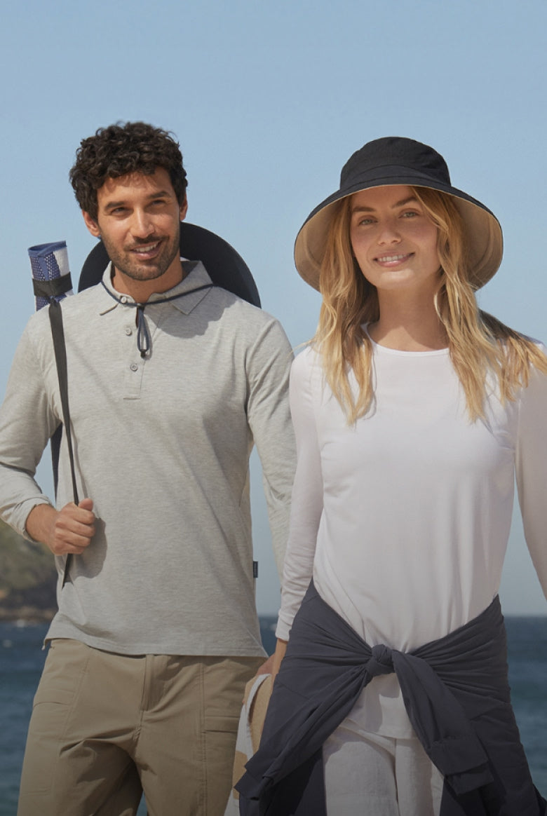 Man and woman standing on a beach with a clear blue sky.